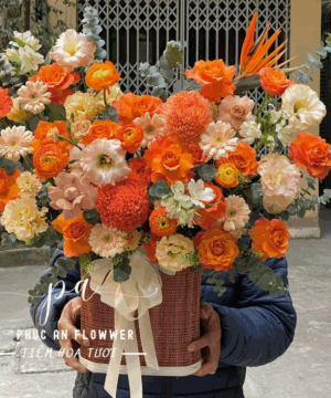 Giỏ hoa tông cam nổi bật với hoa hồng cam, ranunculus, cúc mẫu đơn và hoa phụ cao cấp, thiết kế sang trọng, thích hợp tặng sinh nhật, khai trương, chúc mừng, giỏ hoa tươi cao cấp tông cam ấm áp